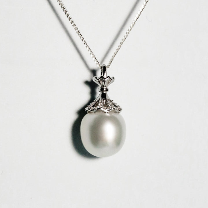 Lustrous near-round South Sea pearl with pink, and blue overtones in a delicate crown mount